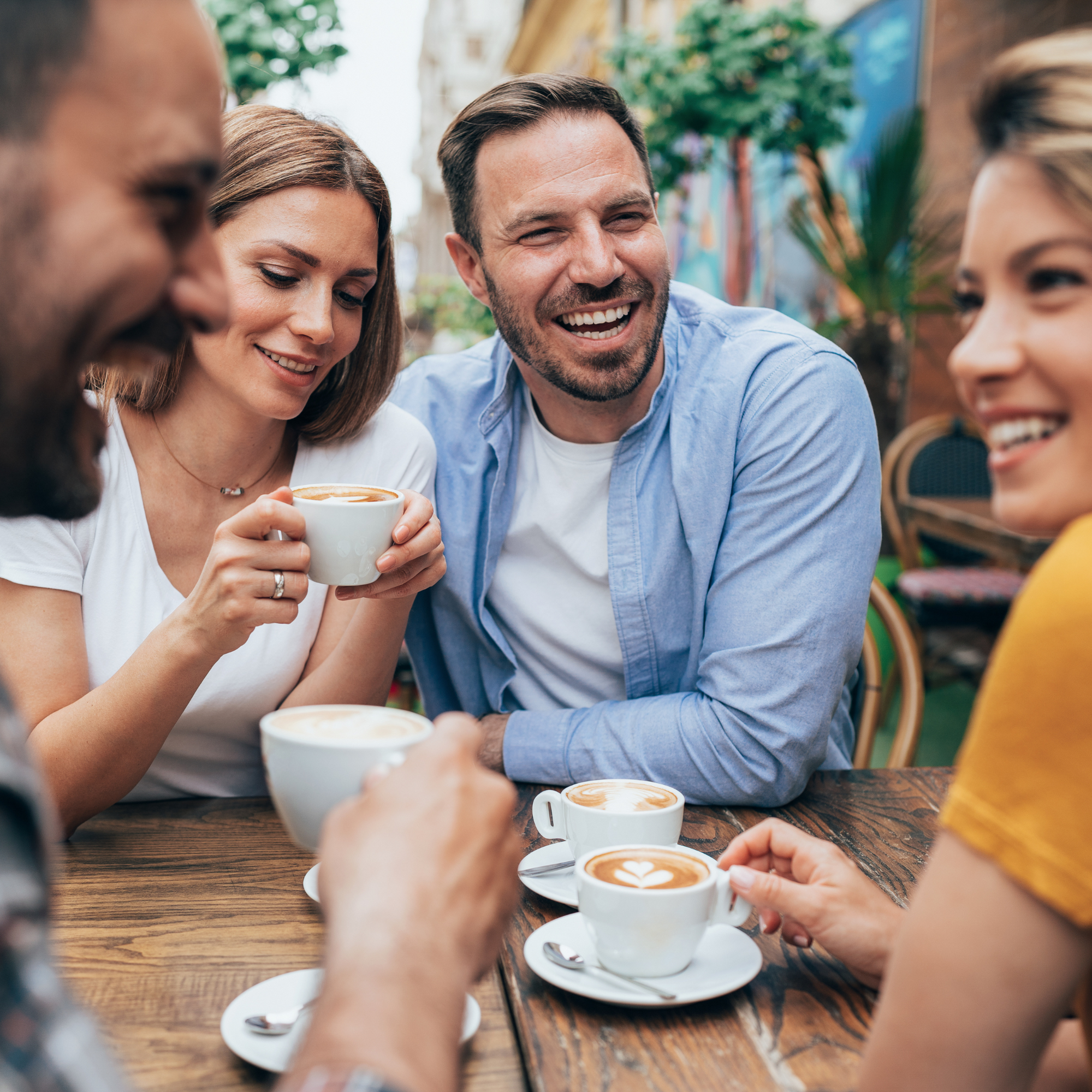 Friends have a talk together outside of a coffeeshop with their coffees