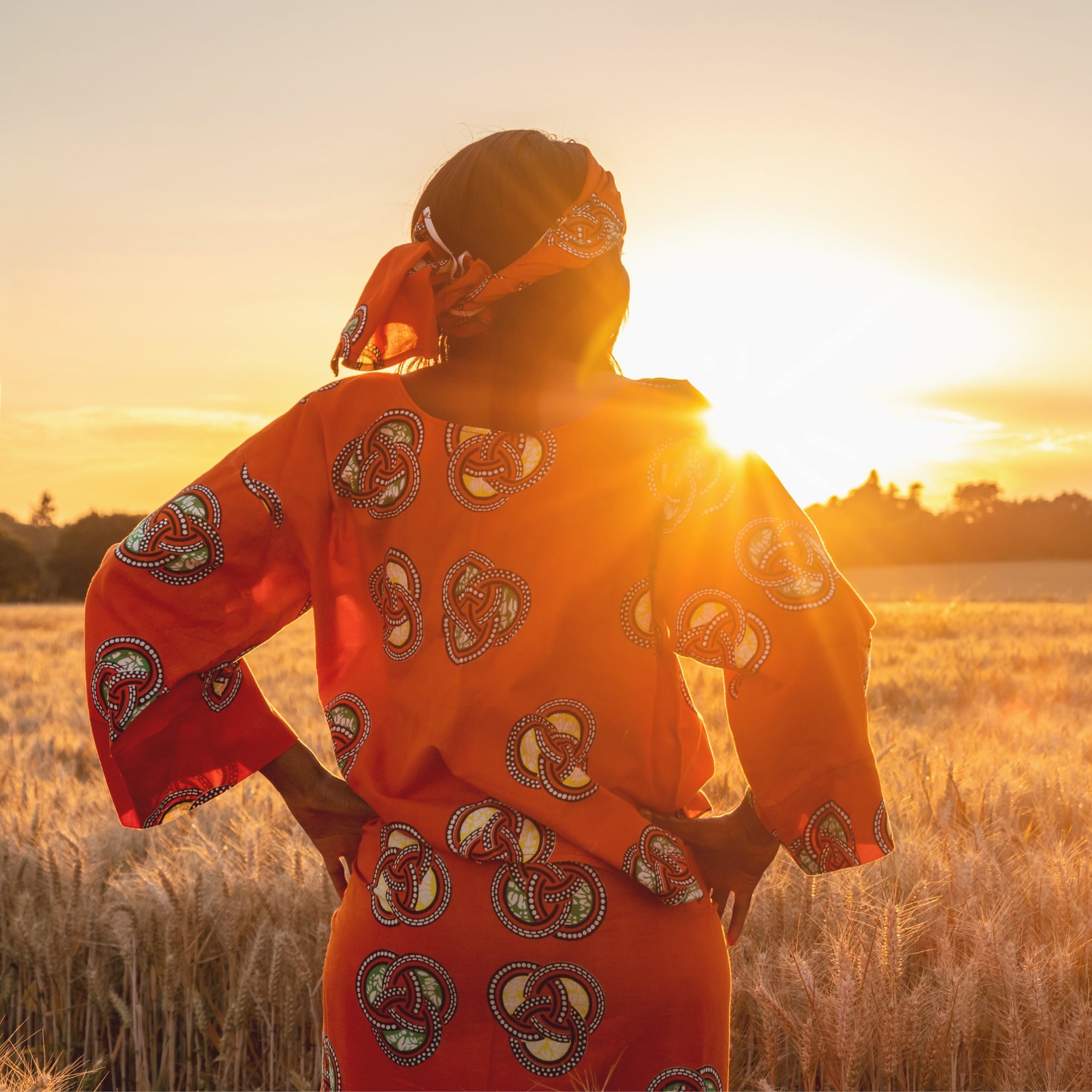 African woman in a crop field at sunset, symbolizing &Better's dedication to eco-friendly products, organic ingredients, and community support.