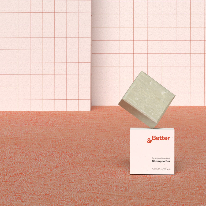 Close-up of &Better Shampoo Bar on a terra cotta background against a white tiled wall. This all-natural, eco-friendly shampoo bar is perfect for a simplified, sustainable personal care routine
