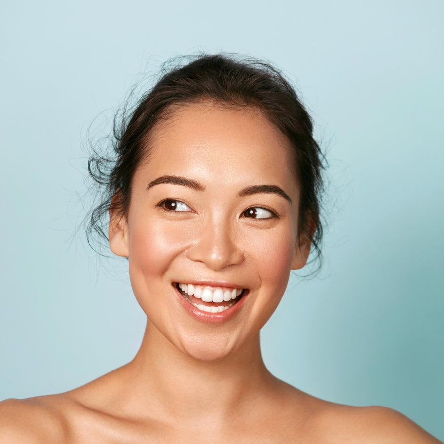 A portrait of a young ethnic woman with a radiant smile, showcasing her glowing skin as a testament to the effectiveness of &Better's all-natural personal care products