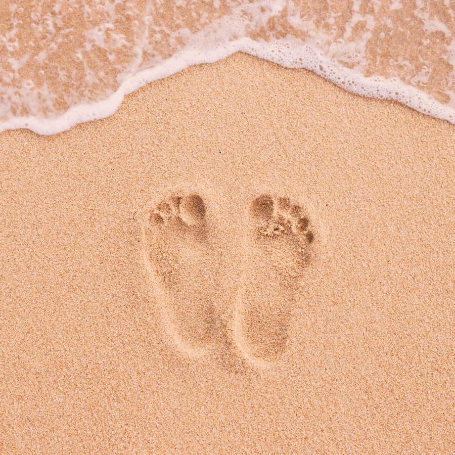 Image of footprints on sandy beach, symbolizing the sustainable steps taken by &Better in their personal care products. The image represents the brand's commitment to making a positive environmental impact with every product.